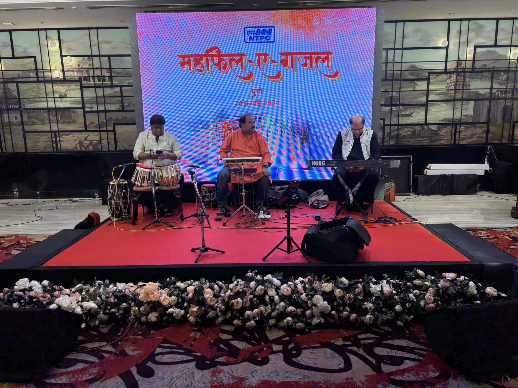 Live ghazal performance on a red-carpeted stage with musicians seated